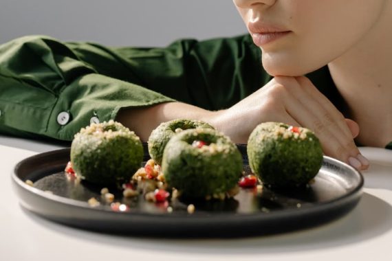 Close-up of spinach pkhali, a Georgian vegan dish, with a woman in green observing.