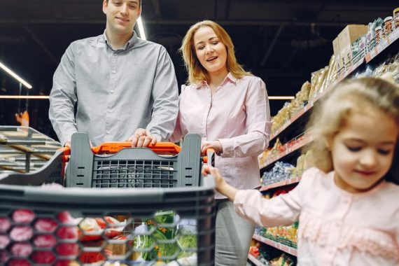 Happy family enjoying a fun shopping trip together in a supermarket aisle.
